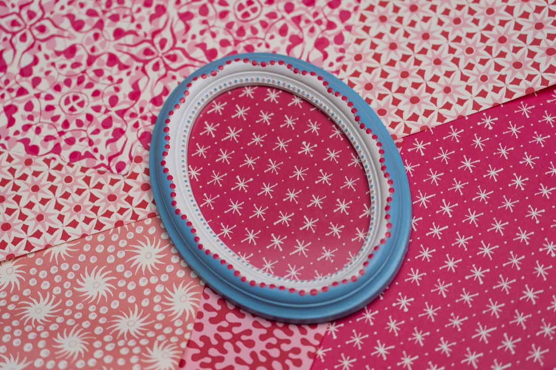 An oval blue frame with pink painted details.