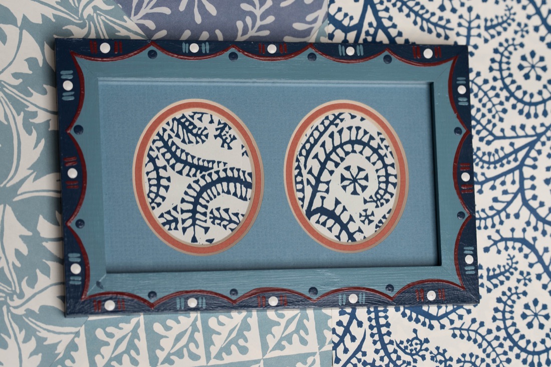 A blue double oval frame with scalloped painted details.