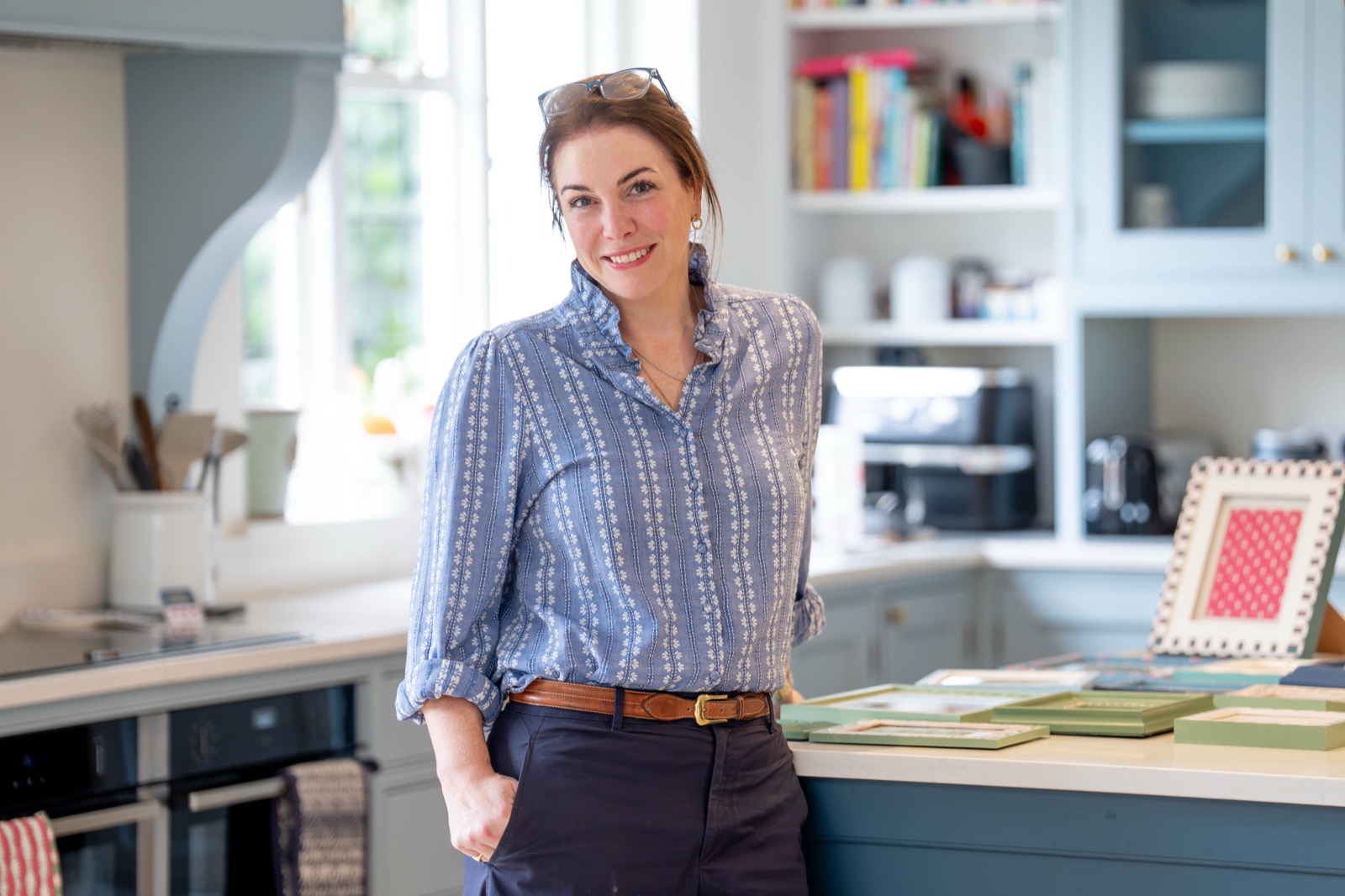 Ellie standing beside her kitchen worktop with hand-painted frames.