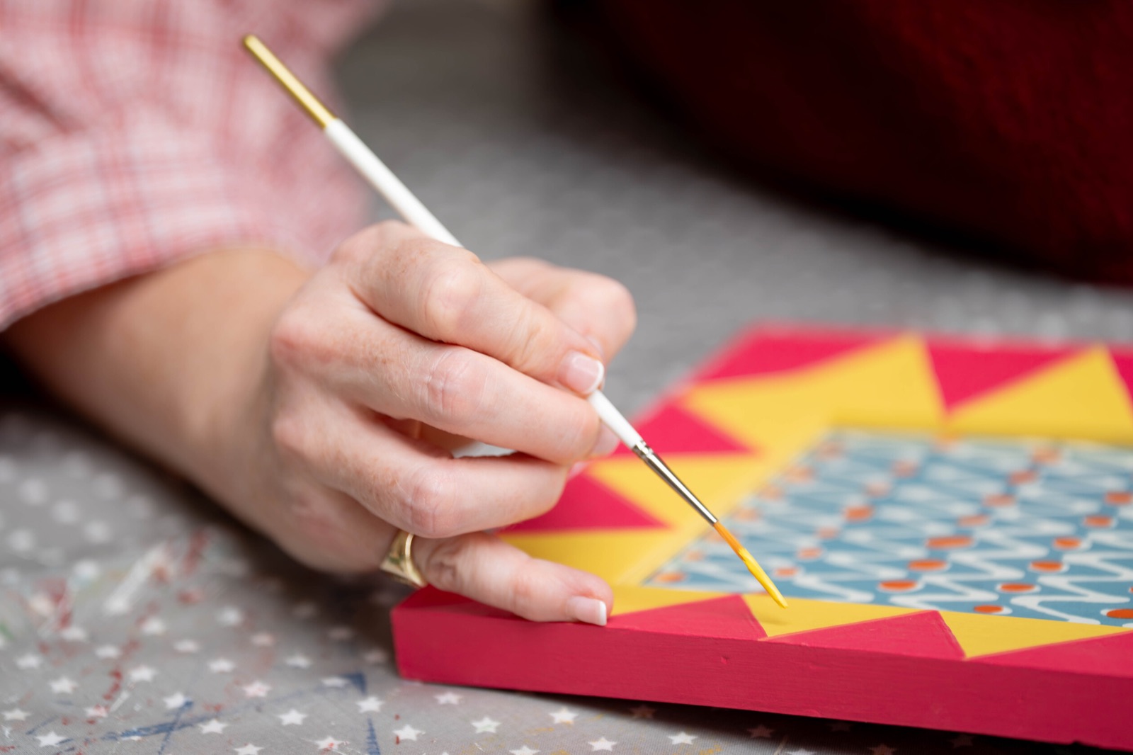 Ellie carefully painting the yellow diamonds on a pink frame.